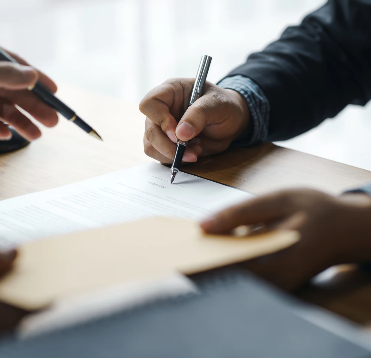 Hands holding pens over paperwork